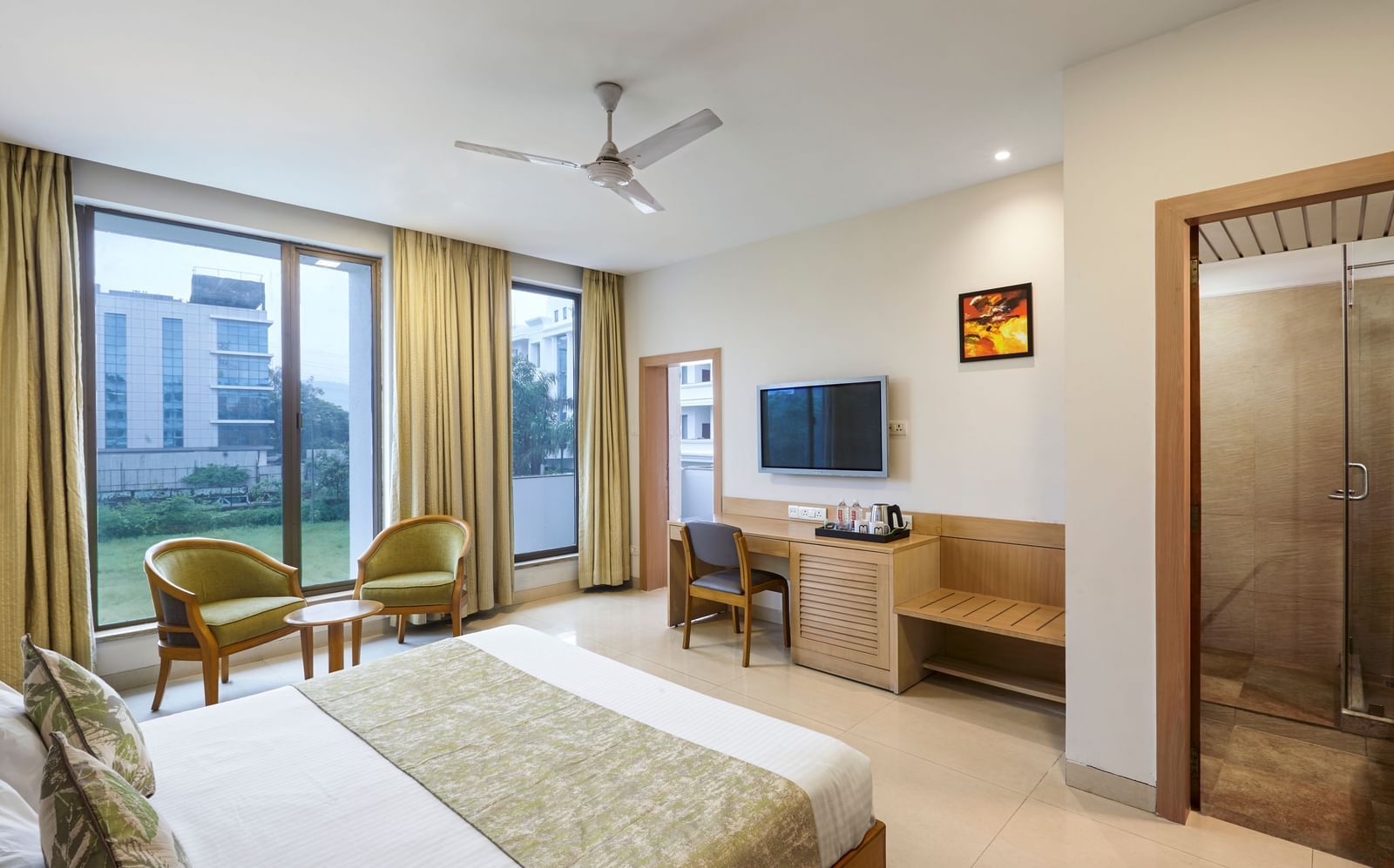 A spacious hotel room at Monday Hotels Mahape, Navi Mumbai, showing the bed, a desk, and the bathroom entrance.