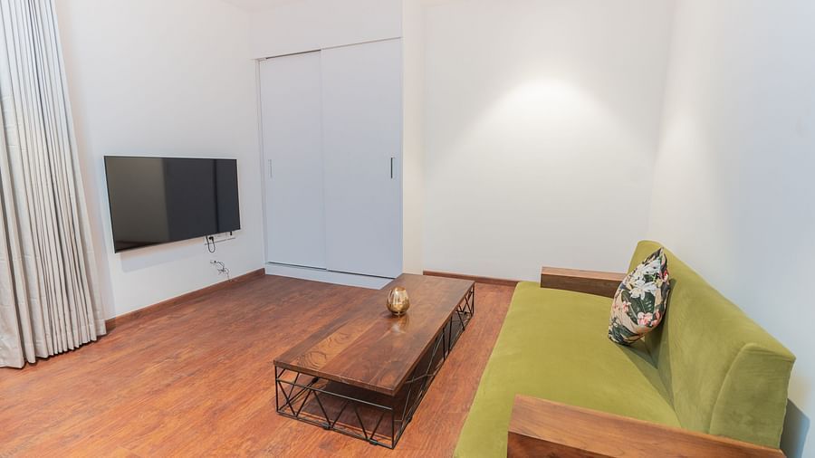 image of a olive green coloured couch placed in front of a wall mounted tv in the family villa two bedroom - Darza Resorts