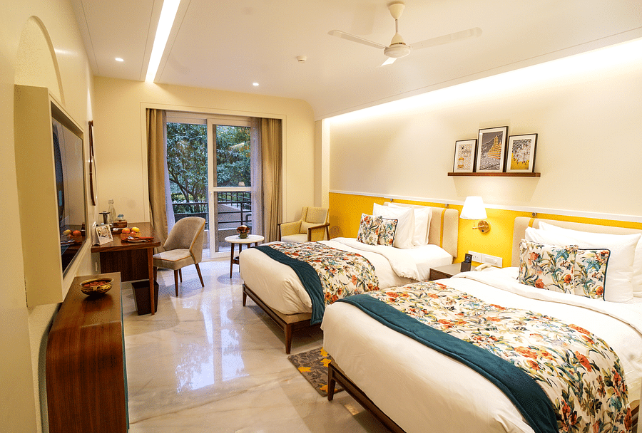 Deluxe Royal Room with two twin beds, good lighting, a TV stand with a wall-mounted TV, a desk with a chair, and a balcony offering a scenic view - Aloha On the Ganges
