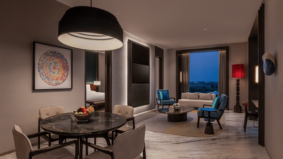 View of the Premium Suite living and dining area at The Residency Signature Madurai with a dining table, pendant light, and warm ambient lighting.