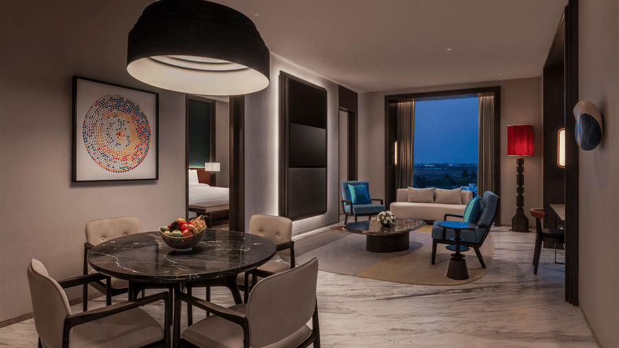 View of the Premium Suite living and dining area at The Residency Signature Madurai with a dining table, pendant light, and warm ambient lighting.