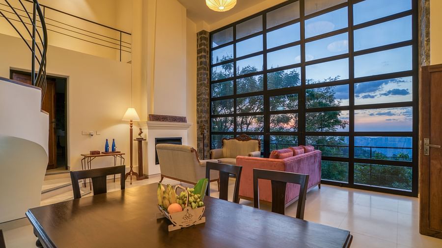 An image of a dining area with a window that gives a view of the outside world | Mango Hill, Yercaud