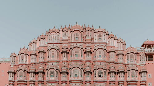 Facade view of Hawa Mahal in Udaipur with blue sky in the background.