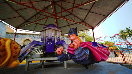 Batman Jet ride with a Batman figure seat and a leopard-print seat on arms around a purple central tower, under a red-framed canopy at MGM Dizzee World, Chennai.