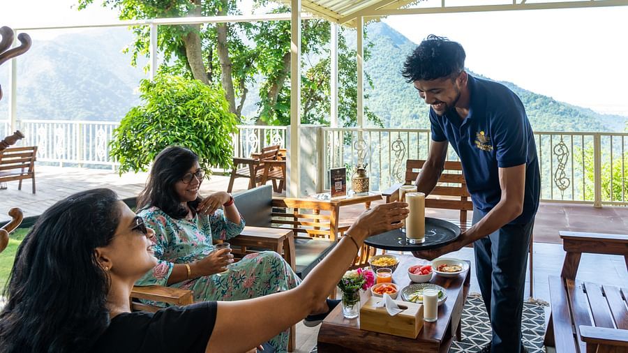 a waiter serving beverages to two women at Neer Ganga Resorts