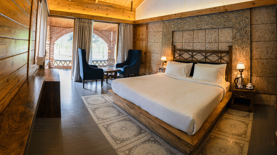 A large bed placed next to the chairs at Superior Room at the Sylvan Retreat, Dehradun.