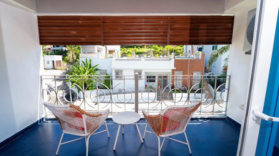 Private balcony with two chairs and a table overlooking a peaceful neighbourhood, offering a bright and relaxing outdoor seating area for your stay in Montego Bay | Hotel 39