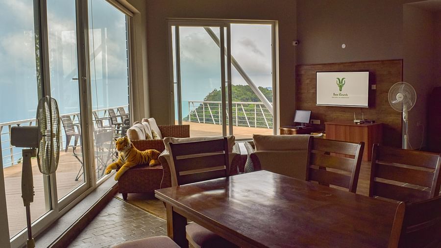  Spacious corner seating area with wide windows and a wooden coffee table at Ibex Resorts, Coonoor (Tapas).