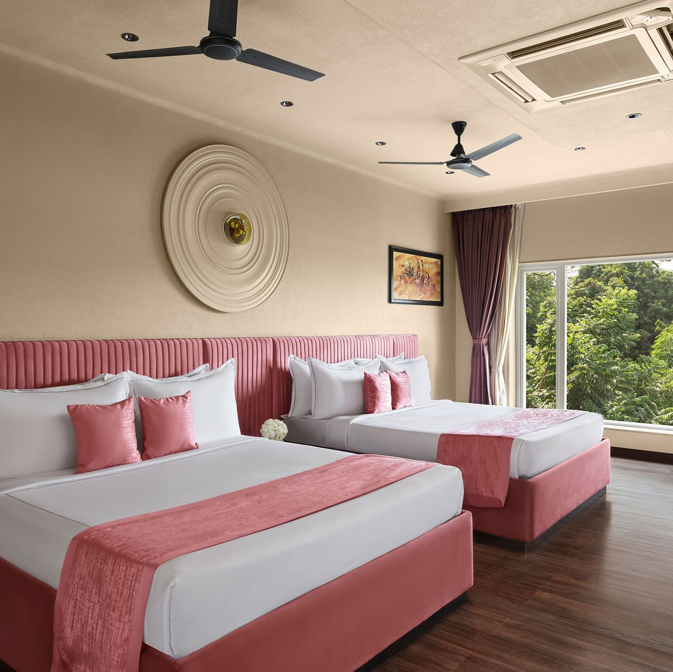Super Deluxe Family Room with two large beds featuring pink and white bedding, and a window overlooking lush green trees at DGV Resort by Treat, Silvassa