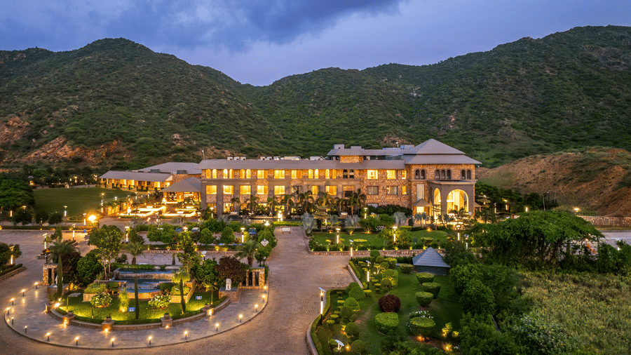 Evening view of Pushkara Resort & Spa, Ajmer, illuminated with warm lights, landscaped gardens and mountain backdrop