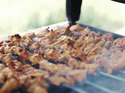 Juicy kebabs being grilled over open flames on skewers.