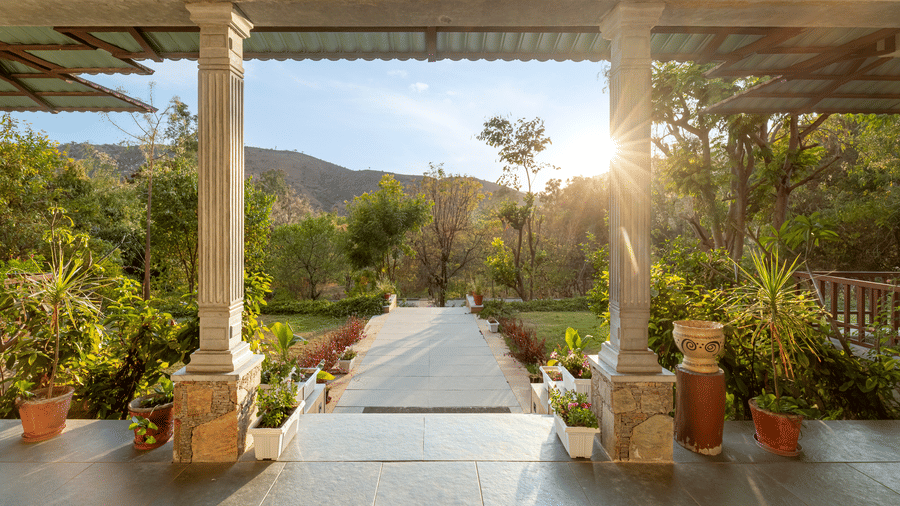 Front porch at The Hunting Lodge, Udaipur, overlooking the lush gardens surrounding the pathway in the middle.
