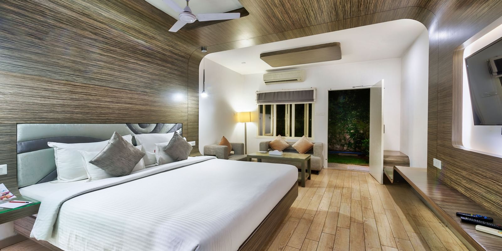 A spacious room with a king size bed, wooden flooring, seating area and ceiling fan at Grande Bay Resort & Spa.