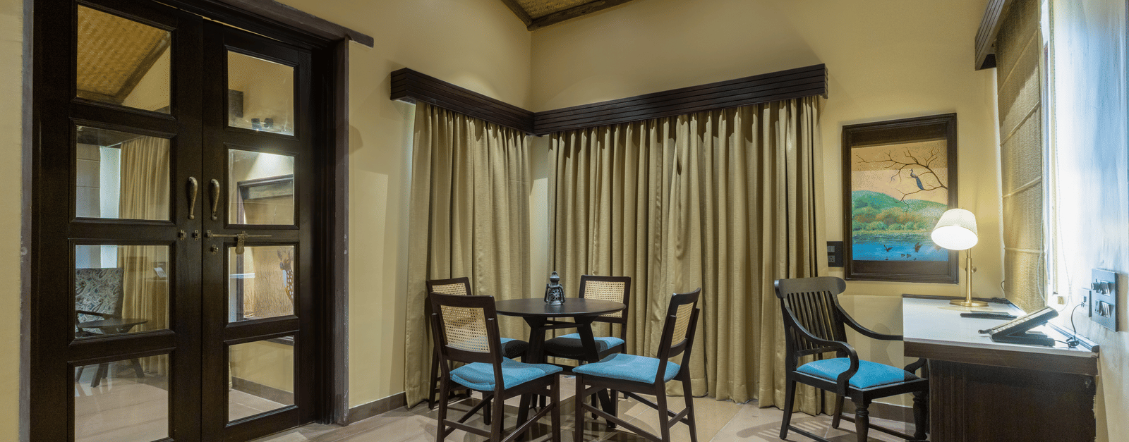 A dining and seating area at Aamaghati Wildlife Resort with stylish furnishings and large windows offering a comfortable space to enjoy meals.