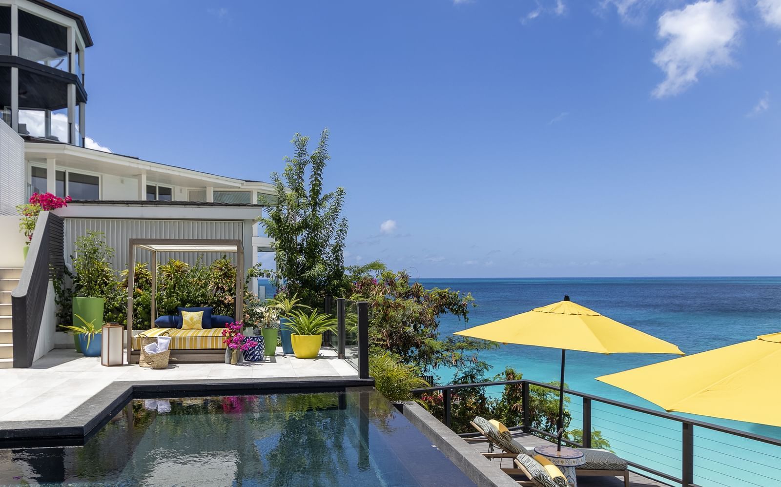 A stylish poolside setting with ocean views, searing and Patio at Tamarind Hills Resort and Villas Antigua, a luxury resort in Antigua offering vibrant, modern relaxation spaces.
