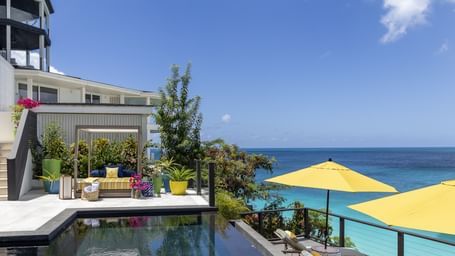 A stylish poolside setting with ocean views, searing and Patio at Tamarind Hills Resort and Villas Antigua, a luxury resort in Antigua offering vibrant, modern relaxation spaces.