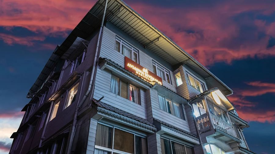 Facade view of Avianna Seven Seas, Darjeeling at dusk with dramatic pink and blue sky, warmly lit windows, and signage glowing on the upper facade.