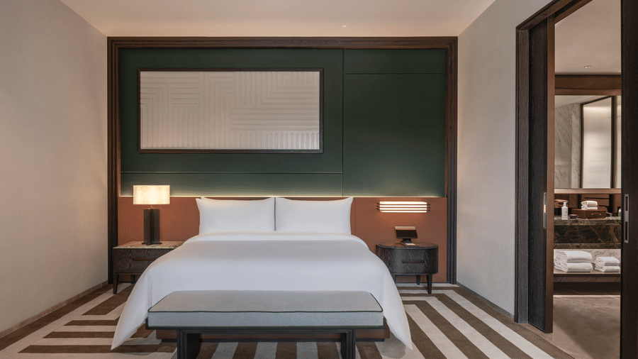 View of the Club Suite at The Residency Signature Madurai with a king bed, green accent wall, striped flooring, and warm ambient lighting.