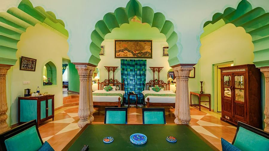 A room with a table, chairs, a decorative archway, and a wardrobe in Tijara Fort-Palace - 19th Century, Alwar.