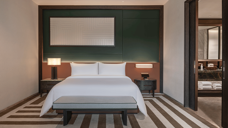 View of the Club Suite at The Residency Signature Madurai with a king bed, green accent wall, striped flooring, and warm ambient lighting.