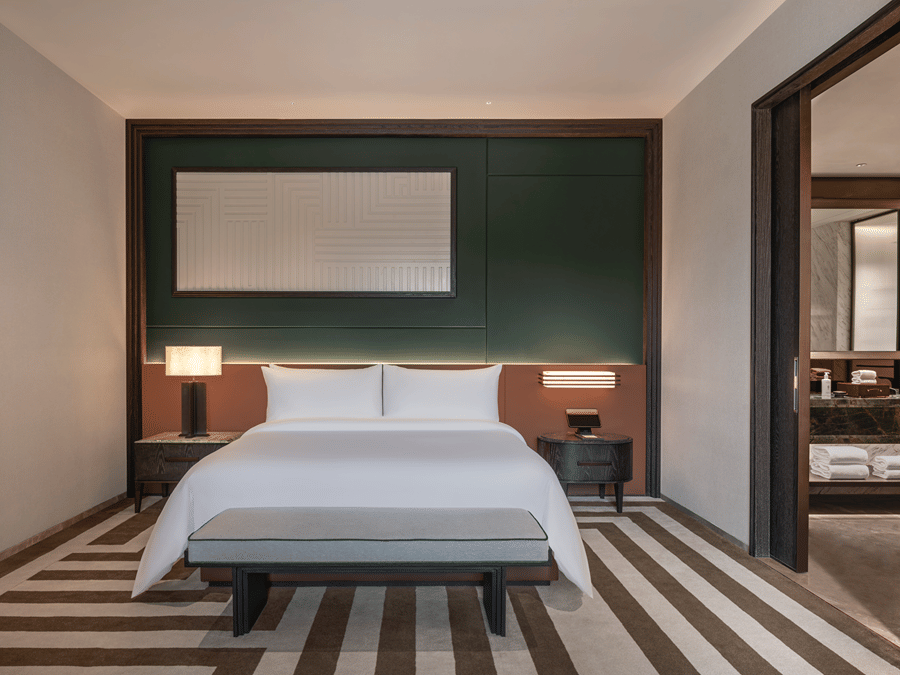 View of the Club Suite at The Residency Signature Madurai with a king bed, green accent wall, striped flooring, and warm ambient lighting.