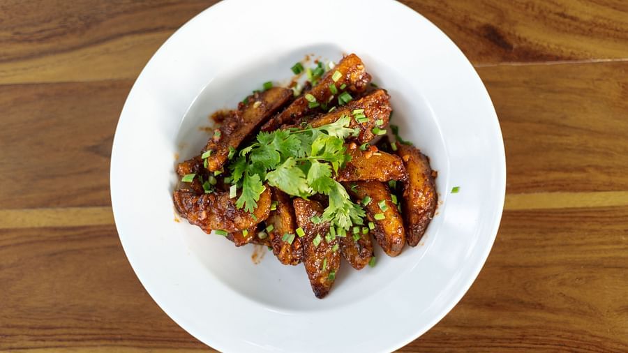image of a white plate with potato wedges topped with fresh coriander leaves