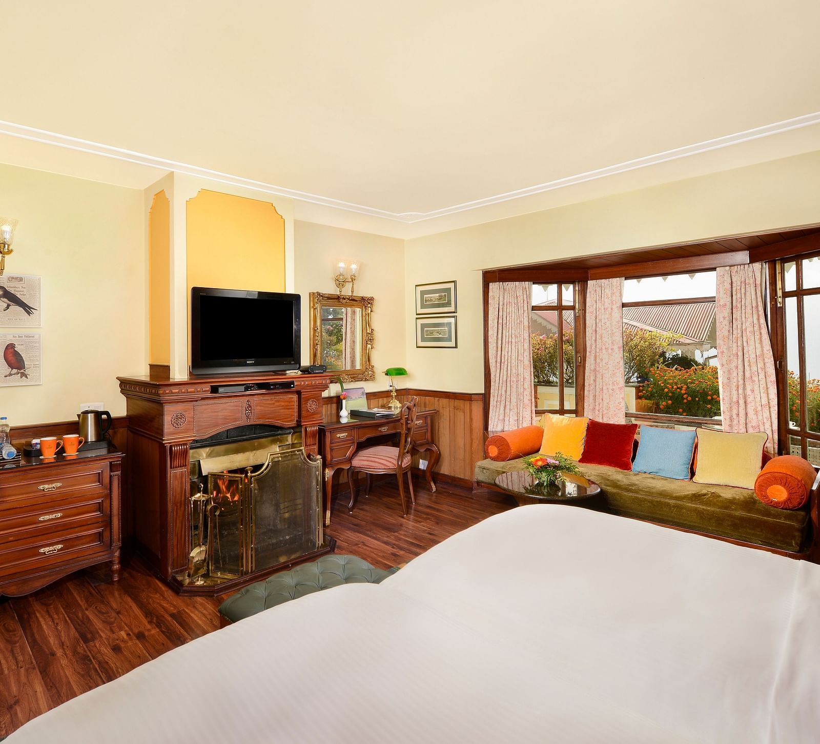 view from the bed overlooking the TV and a seating space by the window - Mayfair Himalayan Spa Resort Kalimpong