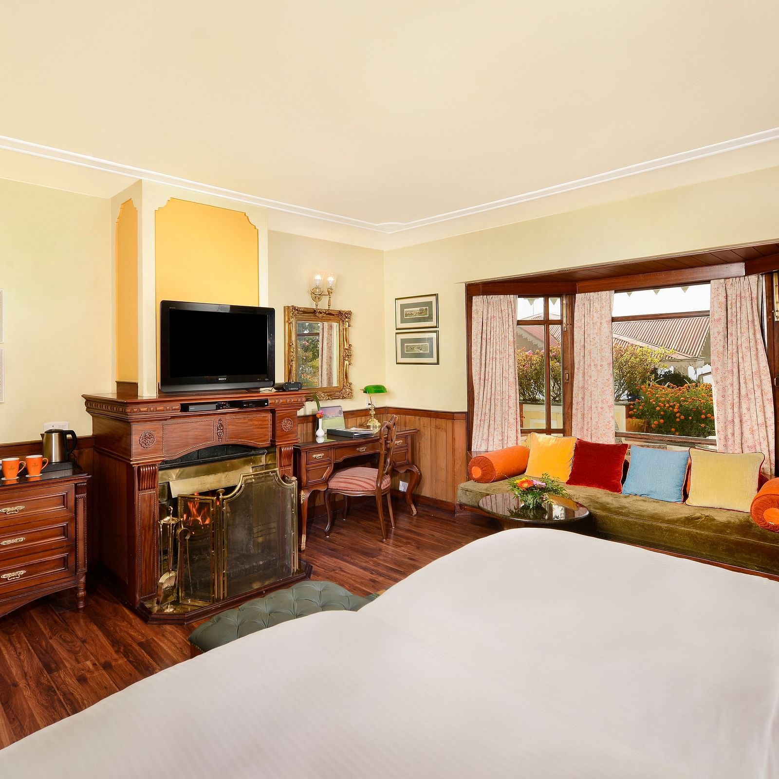 view from the bed overlooking the TV and a seating space by the window - Mayfair Himalayan Spa Resort Kalimpong