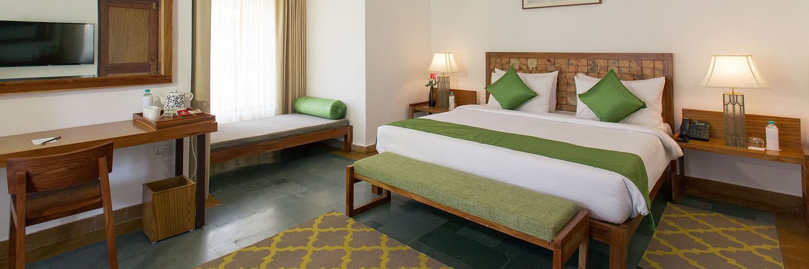 A room at Saraca Resort & Spa Corbett with a double bed, a work desk and chair and a chandelier hanging from the ceiling