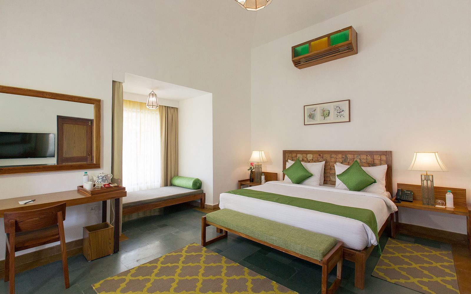 A room at Saraca Resort & Spa Corbett with a double bed, a work desk and chair and a chandelier hanging from the ceiling