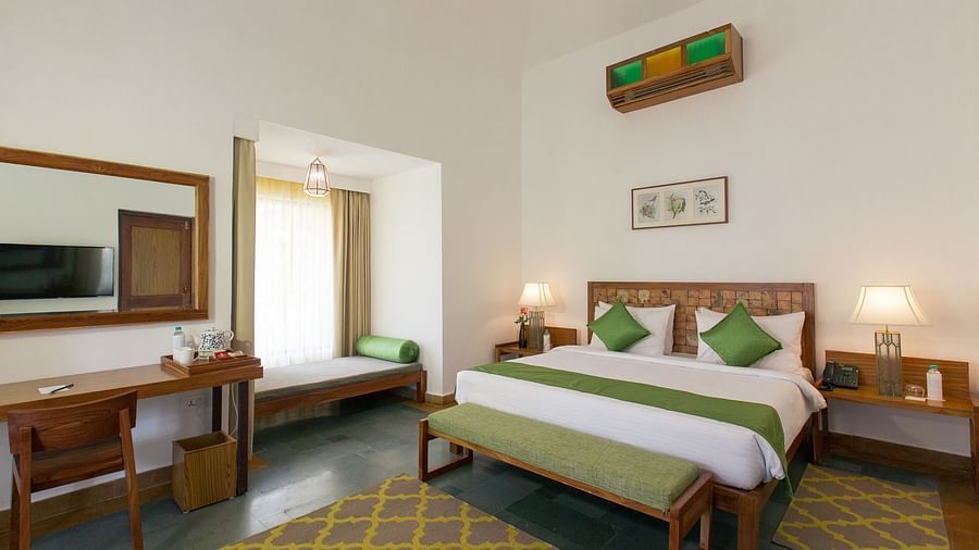 A room at Saraca Resort & Spa Corbett with a double bed, a work desk and chair and a chandelier hanging from the ceiling