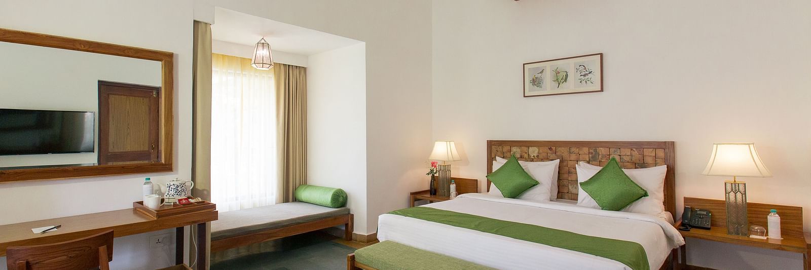 A room at Saraca Resort & Spa Corbett with a double bed, a work desk and chair and a chandelier hanging from the ceiling