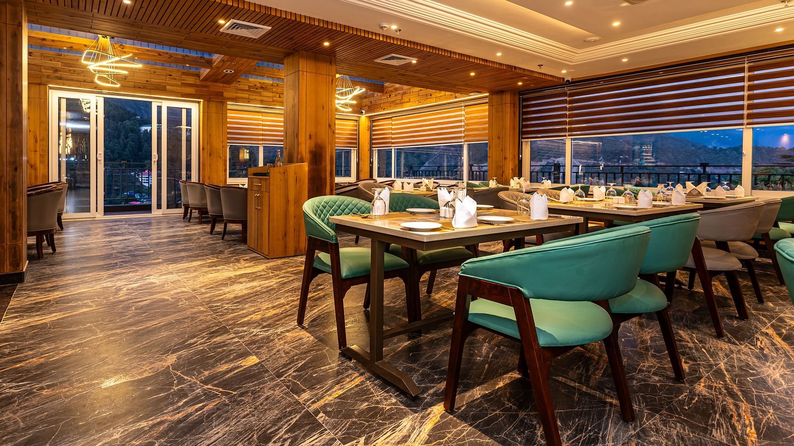 An image of a restaurant with seating arrangement and subtle lighting for decoration - An image of a Deluxe Room with a bed, flat screen TV, work desk and chair - The Belvedere Himalayan Retreat, McLeodganj