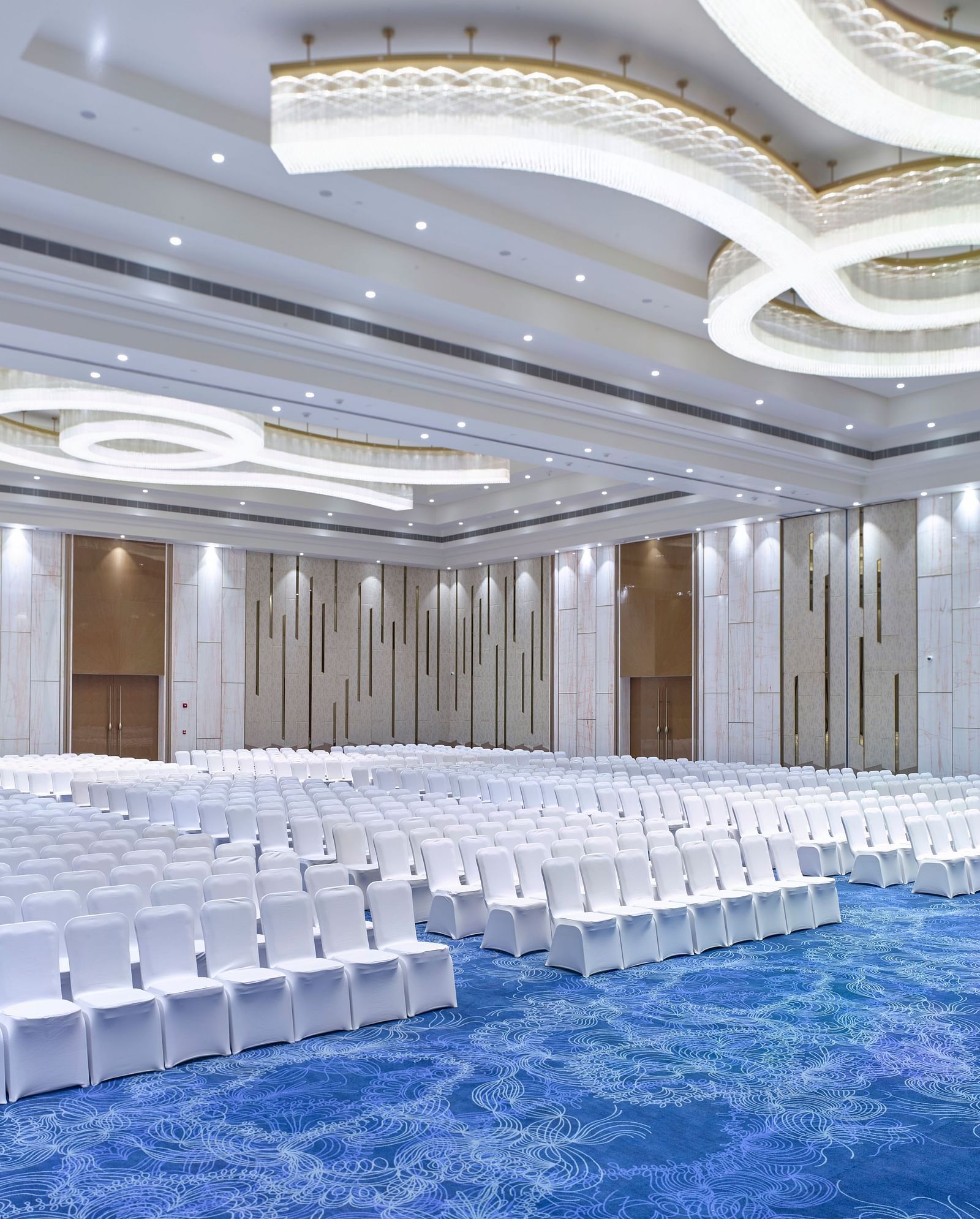 Brightly lit event hall with carpet and modern lighting design at Merlis Hotel, Coimbatore.