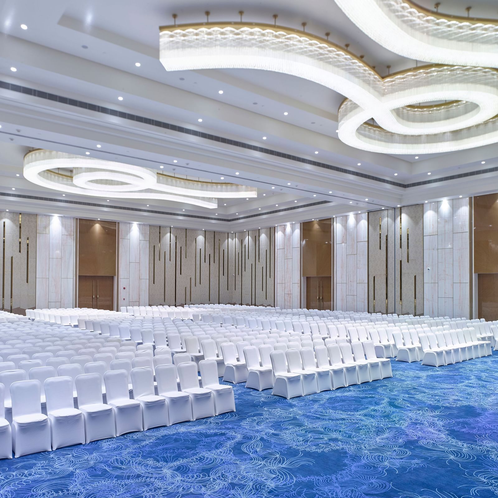 Brightly lit event hall with carpet and modern lighting design at Merlis Hotel, Coimbatore.