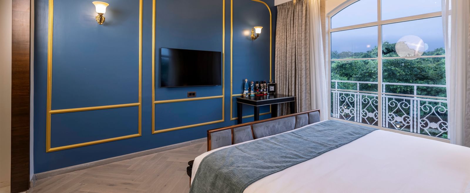 A turquoise coloured wall with golden lines and a wall-mounted television at the Suite at Imperial Goa.