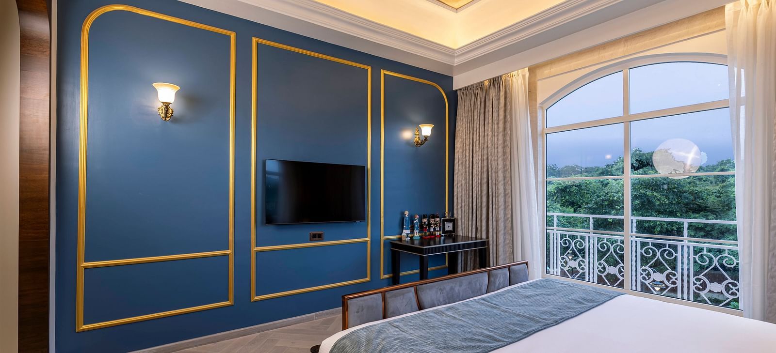 A turquoise coloured wall with golden lines and a wall-mounted television at the Suite at Imperial Goa.