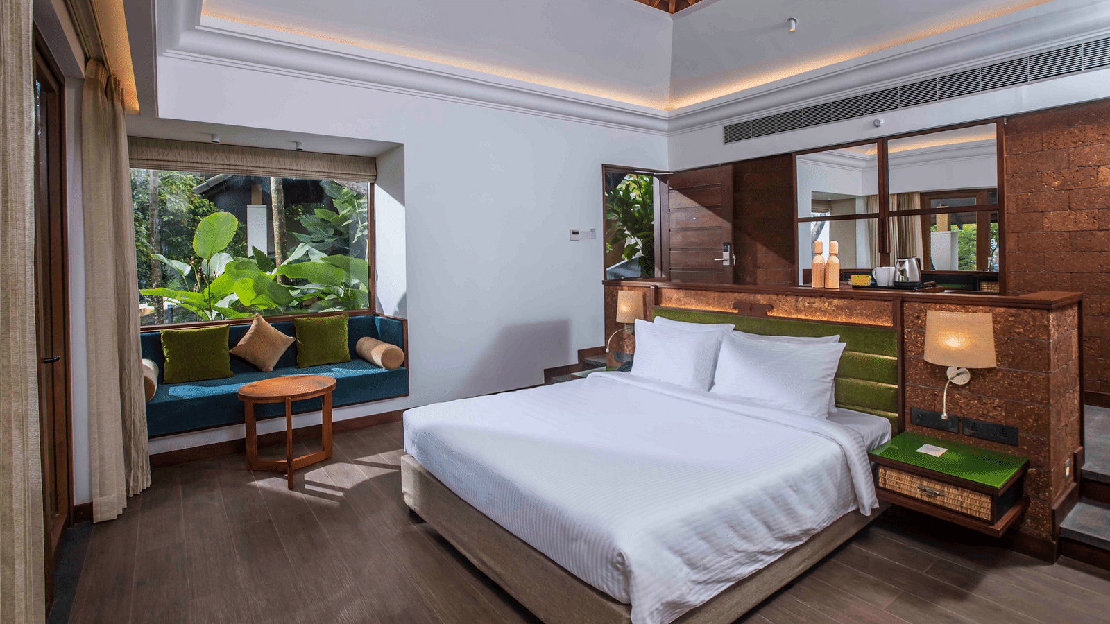 An image of a hotel room in Wayanad with a large bed and cosy furniture offering an experience of jungle stay in Wayanad - GReaT trails Wayanad by GRT Hotels