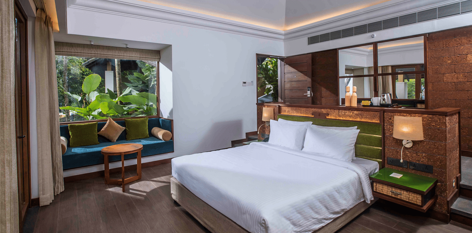 An image of a hotel room in Wayanad with a large bed and cosy furniture offering an experience of jungle stay in Wayanad - GReaT trails Wayanad by GRT Hotels