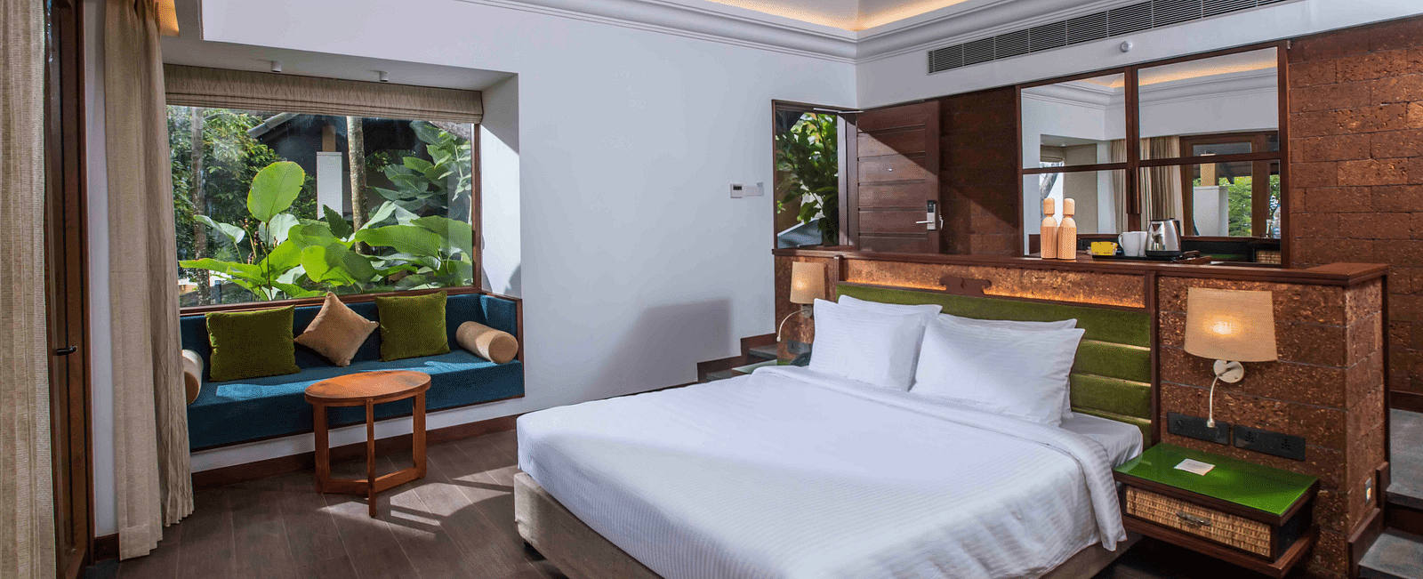 An image of a hotel room in Wayanad with a large bed and cosy furniture offering an experience of jungle stay in Wayanad - GReaT trails Wayanad by GRT Hotels