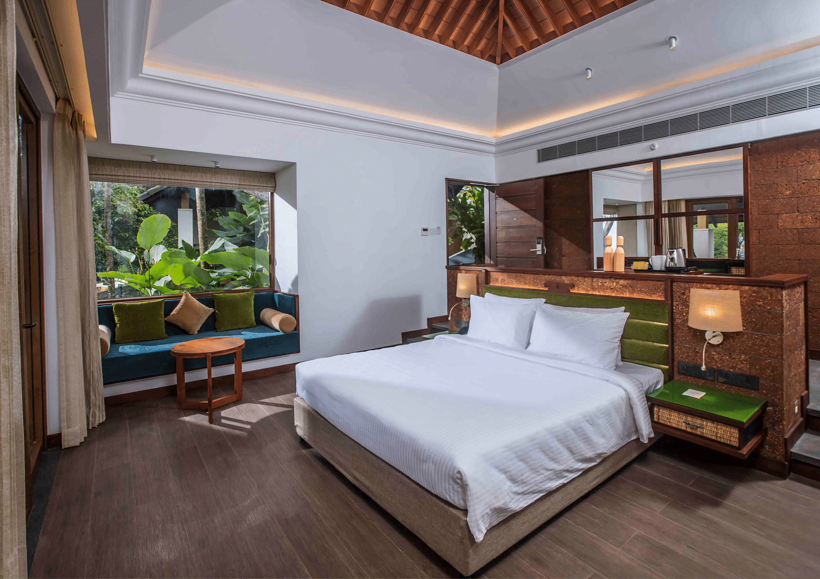 An image of a hotel room in Wayanad with a large bed and cosy furniture offering an experience of jungle stay in Wayanad - GReaT trails Wayanad by GRT Hotels