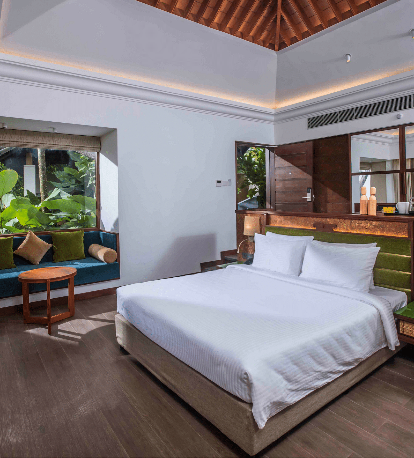 An image of a hotel room in Wayanad with a large bed and cosy furniture offering an experience of jungle stay in Wayanad  - GReaT trails Wayanad by GRT Hotels