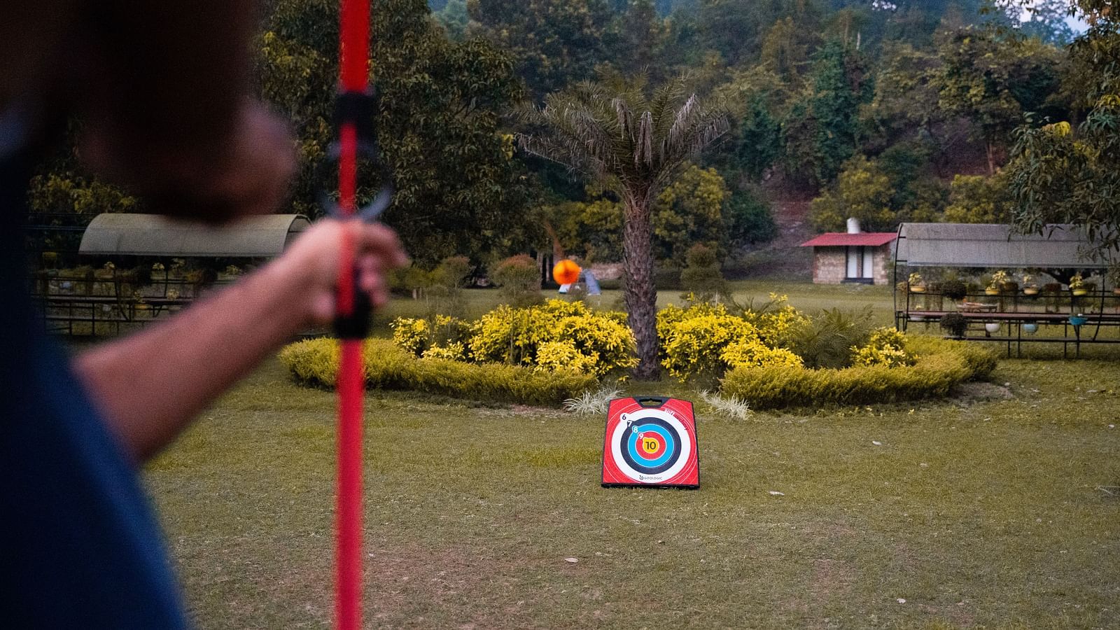 A man practicing archery at A man flying a kite at The Sylvan Retreat, Dehradun.