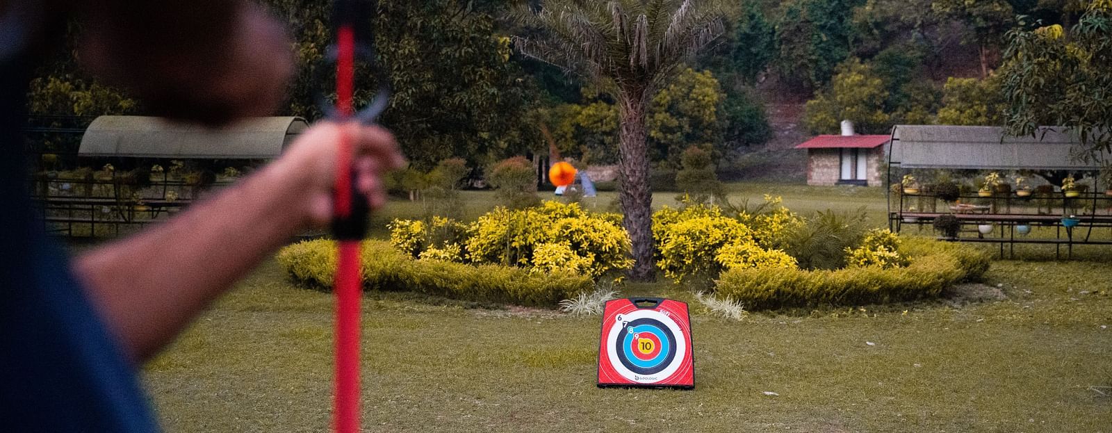 A man practicing archery at A man flying a kite at The Sylvan Retreat, Dehradun.