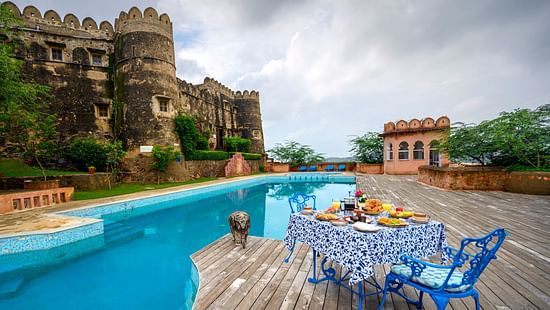 Hill Fort Kesroli 14th Century Alwar - image of a table and chair facing the property's swimming pool