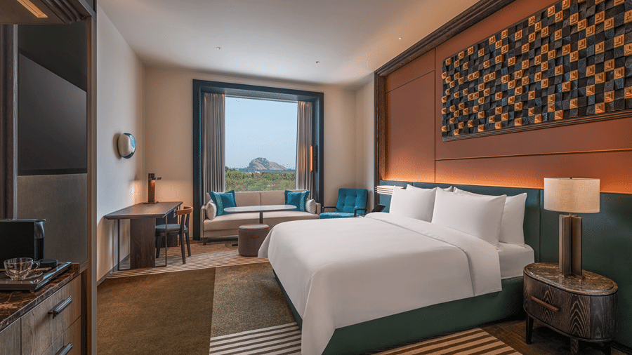 A Premium King Room at The Residency Signature Madurai featuring a neatly made bed, a large window, a wall-mounted TV, and contemporary decor.