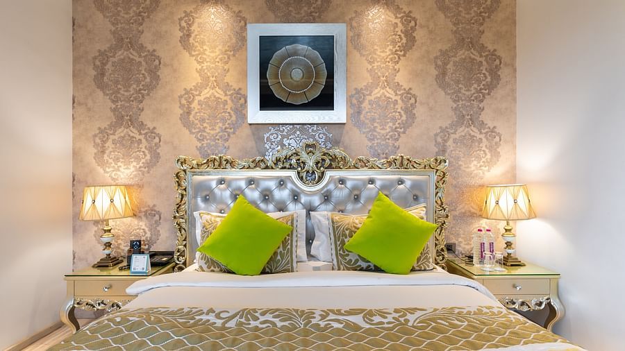 A spacious bed with a photo frame over the headboard, flanked by two bedside tables with warm lighting at Crescent Spa & Resort, Indore