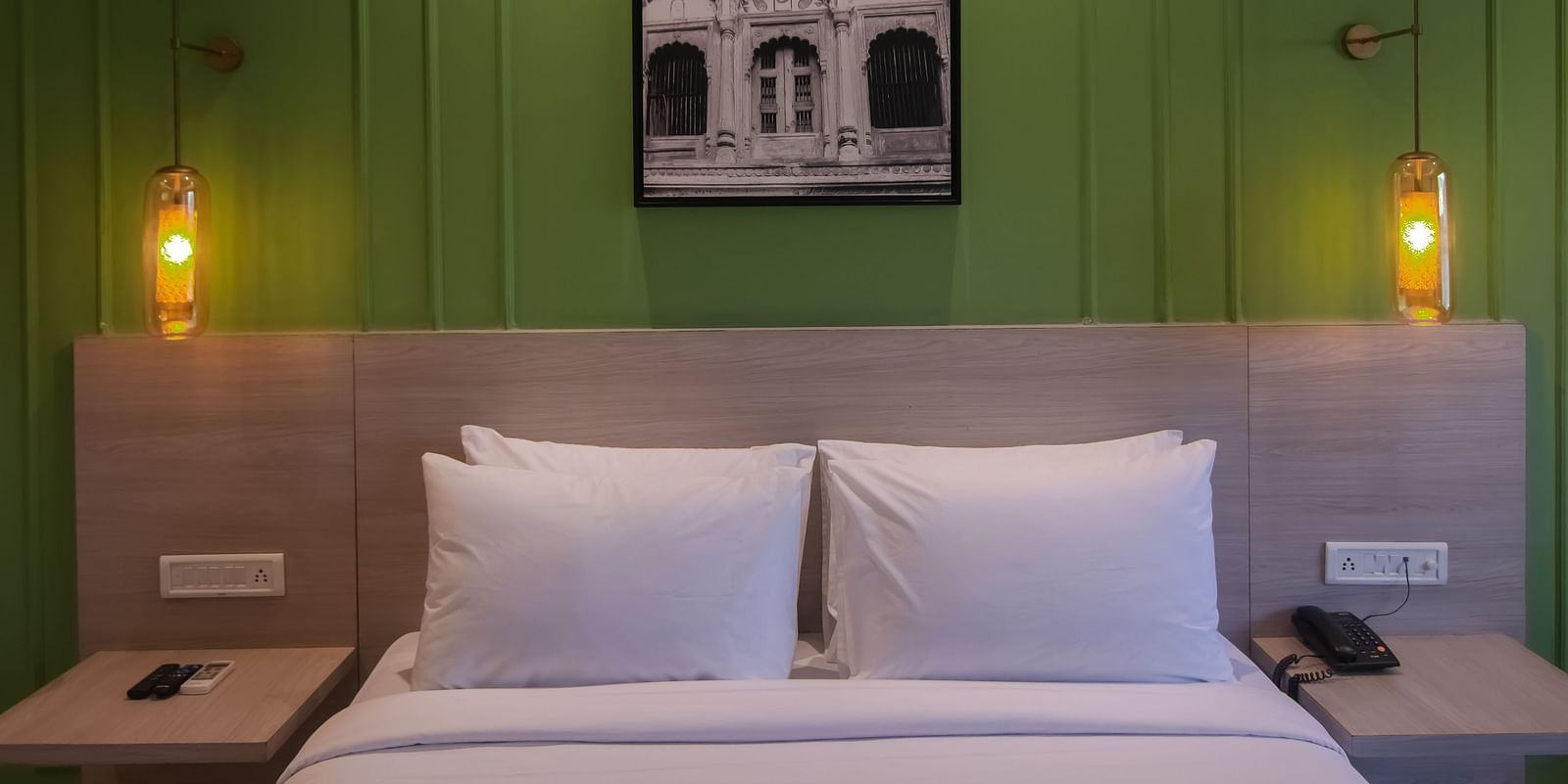 A hotel bedroom with a large bed placed under lamps hanging from the top - Wonder Hills