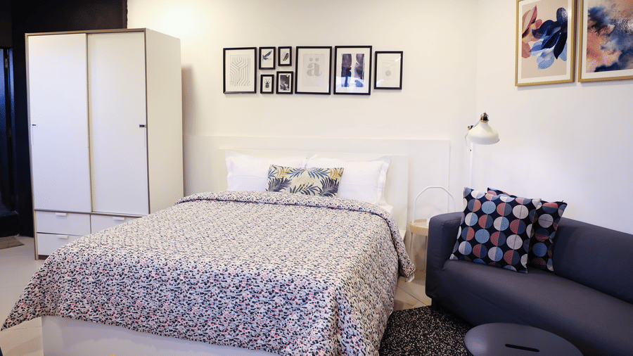 A well-furnished room with a bed, seating area, wardrobe, and modern lighting at Wabi - Sabi by Alamiko, Juhu.