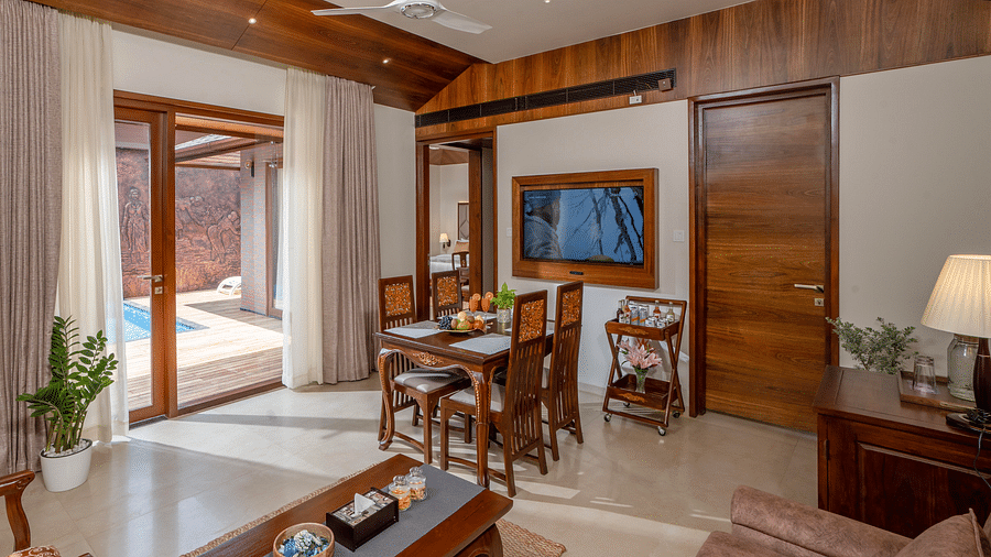 Luxurious living area with wooden decor, dining table, TV, and access to a private pool - Uday Backwater Resort